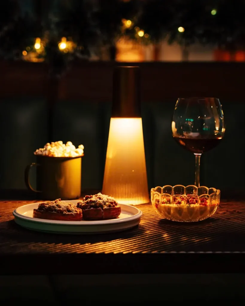 A glass of red wine and a candle on a table in the dimly lit room